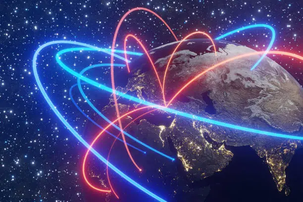 Photo of Blue and red neon glowing light trails orbiting around the planet Earth with starry outer space as background. Illustration of the concept of global connection and international communication