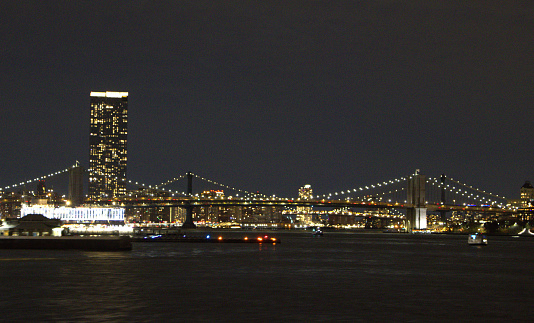 Nighttime view of the lights on the Brooklyn, Manhattan and Williamsburg Bridges. Taken from atop a ferry deck in the middle of the East River.
