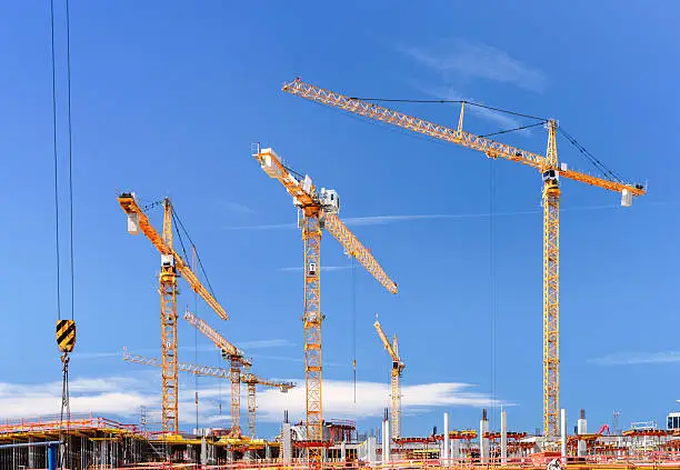 Major construction site with multiple cranes and unrecognizable workers in Germany.