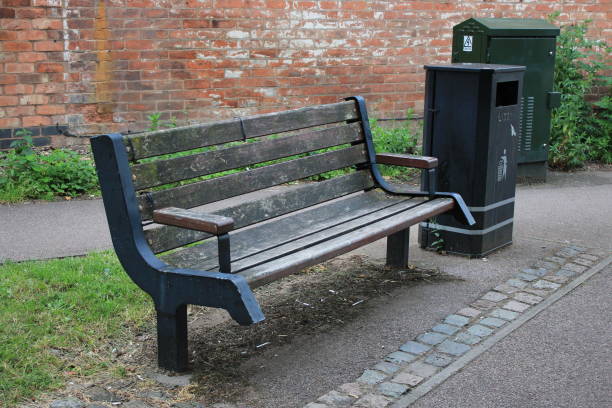 istock Public wooden bench with Black litter bin UK 1732226775