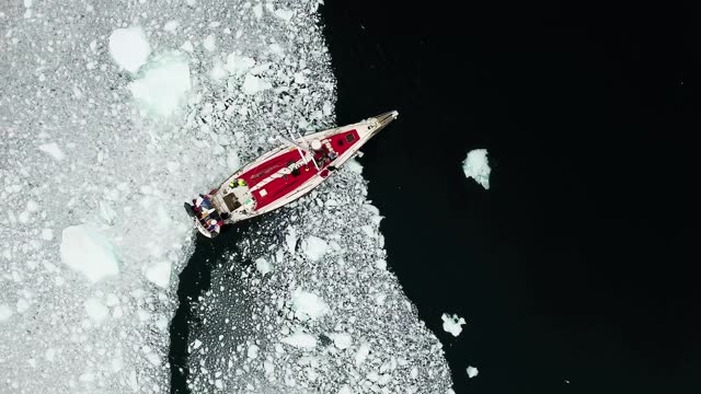 Aerial drone footage of an amphibian boat sailing among icebergs in Jokulsarlon stock video
