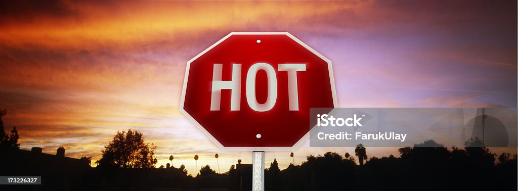 Road sign in red and white with hot written on it Another one of the road sign series of concept images. The word "HOT" written on a stop sign. Sign is placed in the middle of a landscape with a fiery sky. The image is a combination of two photos, both are shot on film with a panoramic camera. Heat Wave Stock Photo