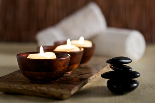 SEVERAL MORE IN THIS SERIES. Floating aromatherapy candles in wooden bowls and black massage stones rest in a zen spa atmosphere.  Very shallow DOF.