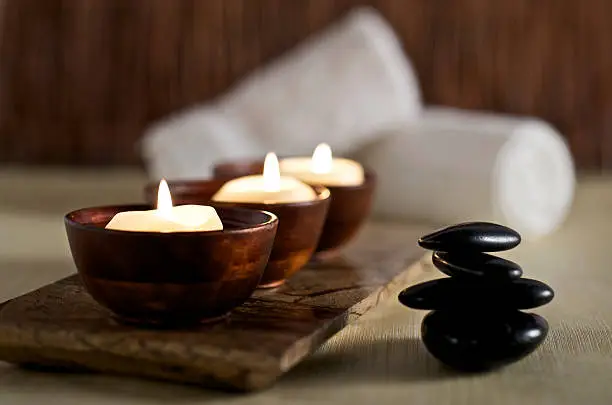 Photo of Lit candles and black massage stones in Zen spa