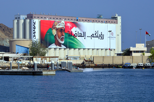 Muttrah, Muscat, Oman: cereals pier at Port Sultan Qaboos - grain handling facilities - cereals silos with large canvas with Sultan Qaboos and the Omani flag, with the motto \