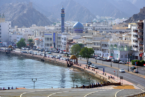 Muttrah, Muscat, Oman: the corniche - Al Bahri Road, facing the Gulf of Oman / Arabian sea, location of Sultan Qaboos Port - historic downtown district with traditional architecture and in the center the Mosque of the Great Prophet, Al Rasool Al A'dham aka Al Shjaiah - Al Hajar Mountains in the background.