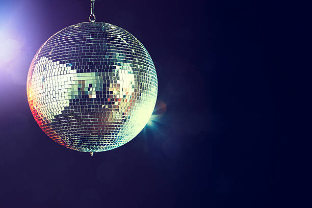 Disco Ball A shining disco ball glitters and spins in a dance club at night, reflecting the various colored lights.  Horizontal with copy space. clubbing stock pictures, royalty-free photos & images