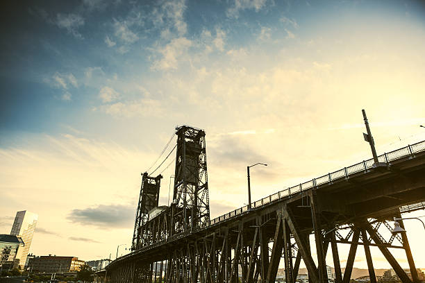 A sunset wide angle view of the steel bridge crossing the Willamette river in Portland, Oregon.  The city is visible in lower image left.  Horizontal with copy space in the blue and orange sky.