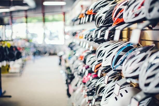 Bicycle Equipment A row of new bicycles helmets hanging on a wall in a shop. Horizontal with copy space. Selective Focus. bicycle shop stock pictures, royalty-free photos & images