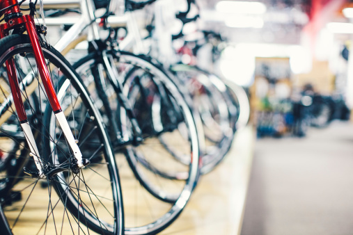 A row of new bicycles sitting in a shop. View of front wheels and tires. Horizontal with copy space. Selective Focus.