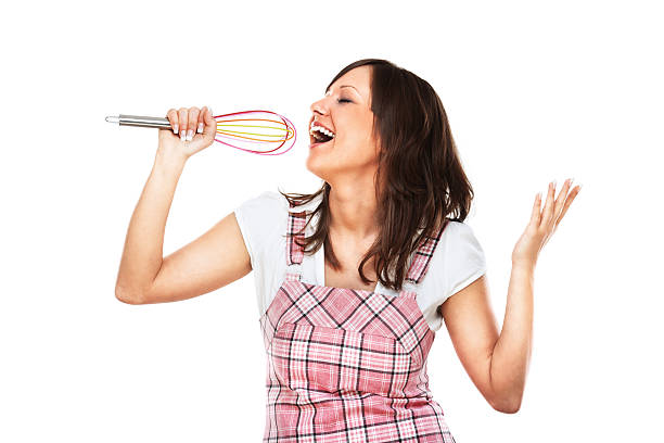 Young woman singing with egg beater stock photo