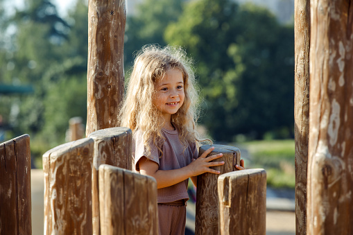 happy little girl playing on the children's wooden playground in the park