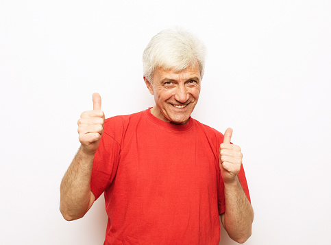 Senior smiling man wearing red t-shirt over isolated background doing happy thumbs up gesture with hands.