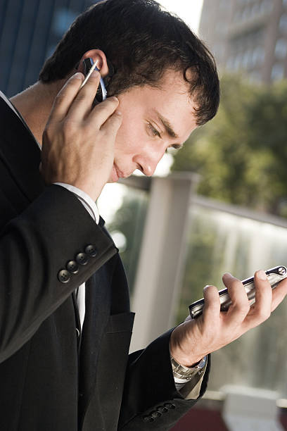 empresario en un teléfono celular con - hbgben100105 fotografías e imágenes de stock