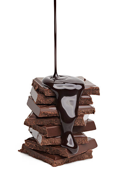 Liquid chocolate being poured on a stack of solid chocolate  Chocolate molten photos stock pictures, royalty-free photos & images