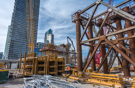 Cranes and heavy machinery next to new uninstalled parts of the new viaduct being built near downtown Miami (I-395 / SR 836 / I-95 Project) , where new luxury housing complexes are being developed.