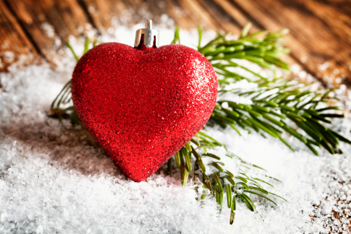 christmas bauble in heart shape and fir branches on snow