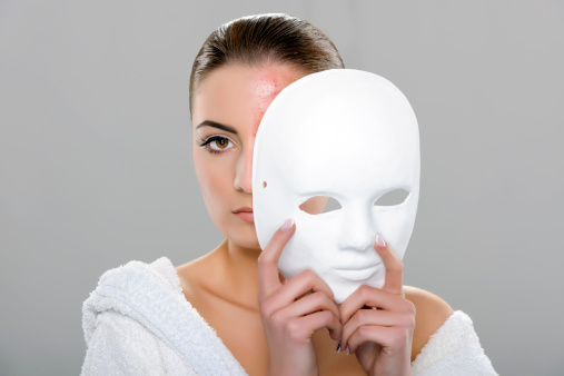 serious young woman holding mask.gray background.beauty concept.