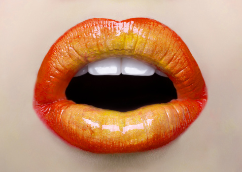 young woman mouth with yellow and orange lipstick.