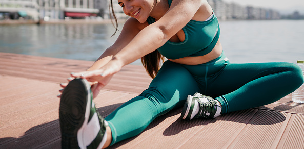 Young beautiful woman stretching legs on the deck