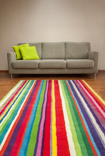 Striped carpet in front of a modern couch.