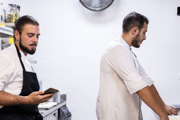 istock A Caucasian chef with long hair is in the kitchen with his mobile phone while his partner works 1732377962