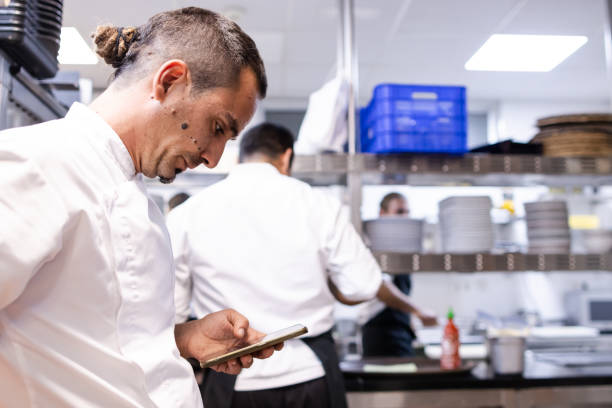 istock Chef with a dread pigtail is looking at his mobile phone to look for a recipe 1732379093
