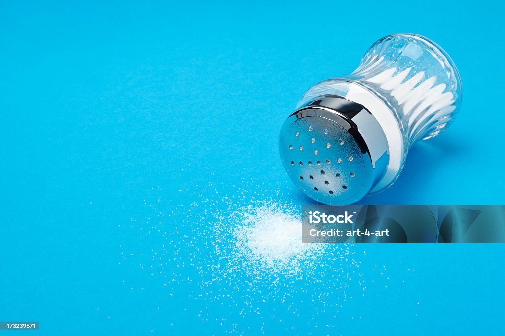 Overturned salt shaker Overturned salt shaker on blue background Salt Shaker Stock Photo