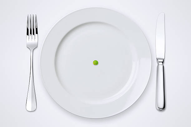 One Green Pea On Plate. Table Setting With Clipping Path. One green pea on plate. Plate, knife and fork with clipping path. green pea photos stock pictures, royalty-free photos & images