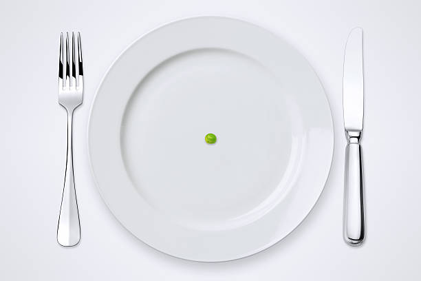 One Green Pea On Plate. Table Setting With Clipping Path. One green pea on plate. Plate, knife and fork with clipping path. white restaurant dishes stock pictures, royalty-free photos & images