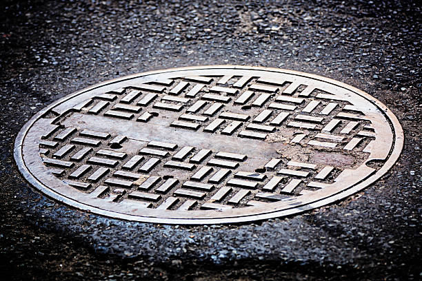 Manhole cover on street Manhole cover on tarmac road.  manhole stock pictures, royalty-free photos & images
