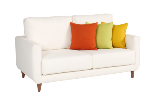 A light gray three seater sofa with armrests and five colored cushions isolated on a blank empty background.