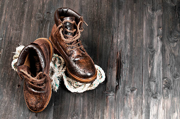 Men's working or hiking boots made of brown leather, vintage look, on wooden background.