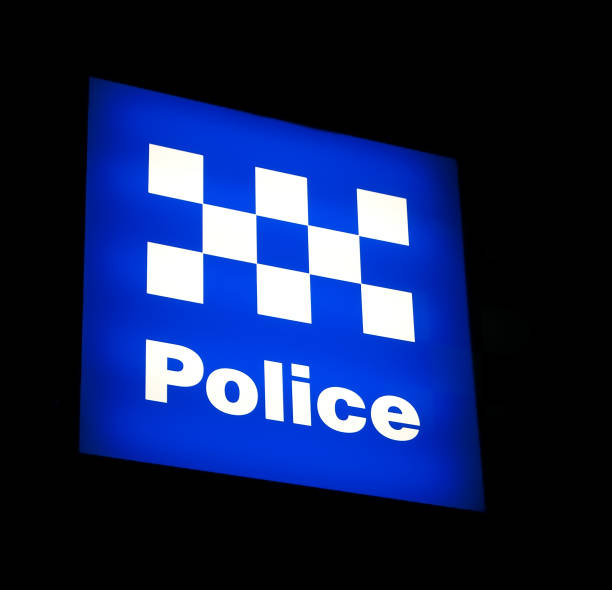 An Australian Police sign in Sydney city, lit at night. Background is pure black and easily extendable.