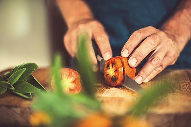 man カティングトマトの素朴なキッチン - vegetable cutter ストックフォトと画像