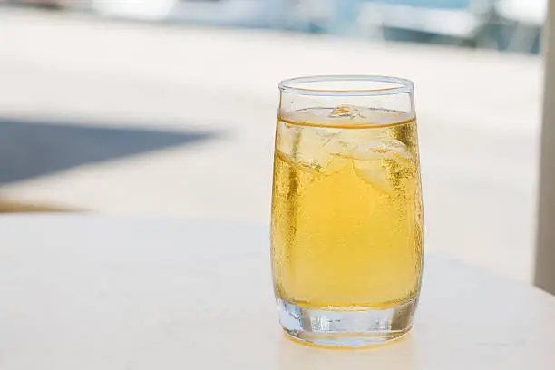 Glass of apple juice with ice on a restaurants table.