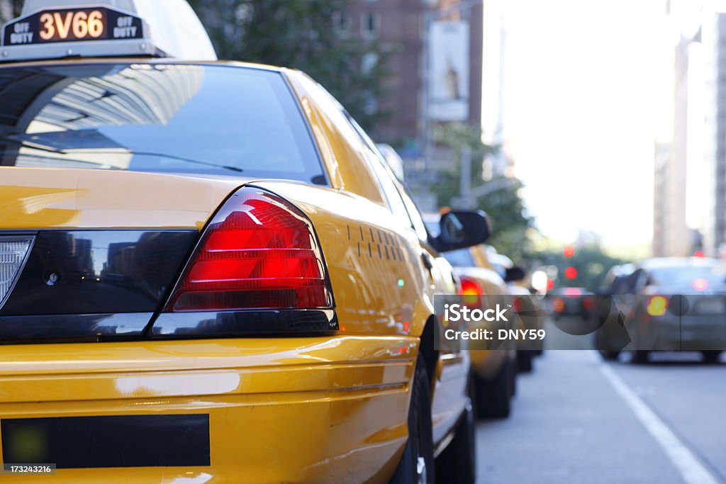 Row of taxis waiting for passengers in New York City a row of taxis waiting for passengers on a busy side street in New York City.  The time is late afternoon as the brake lights from the vehicles can be seen.  One car can be seen trying to make a left hand turn into the waiting line of taxis.  Image is shot with a shallow depth of field. Taxi Stock Photo