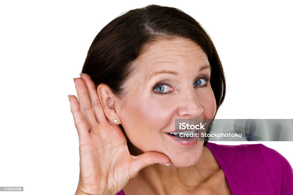 Mature woman listening Mature woman with a cheerful expression holding her hand to her ear for a listening concept Ear Stock Photo