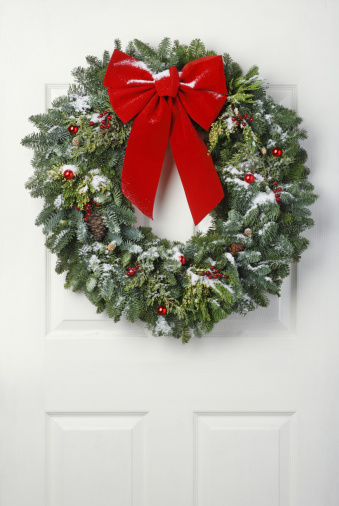 Christmas wreath with fresh snow hanging on door.