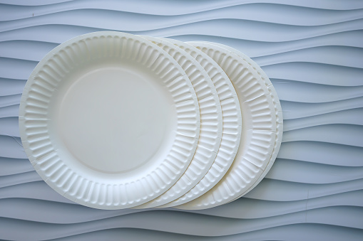 Disposable stack of paper plates on white background. Ecology and Environmental concepts.