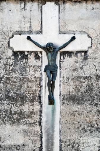 Antique cemetery statue close up: Jesus on cross.