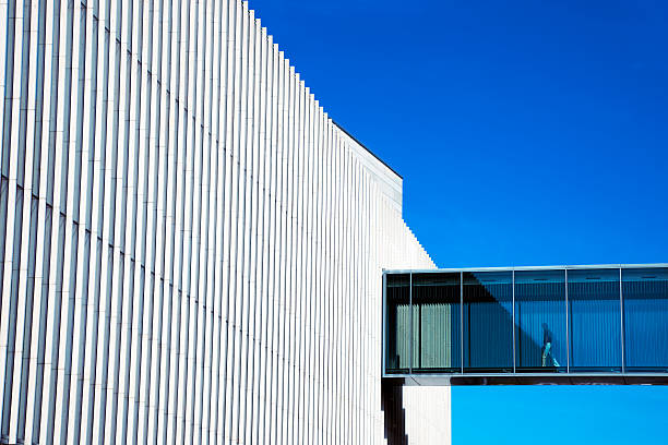 homme passant à travers une passerelle aérienne au bâtiment futuriste - passerelle pont photos et images de collection