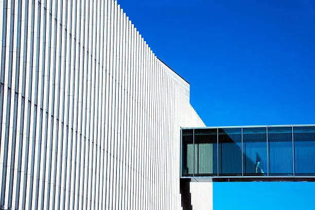 Photo of Man Walking Through Skywalk in Futuristic Building