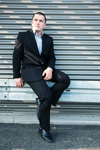 istock Young Businessman Sitting on Crash Barrier, Taking Break in Sunshine 173245571