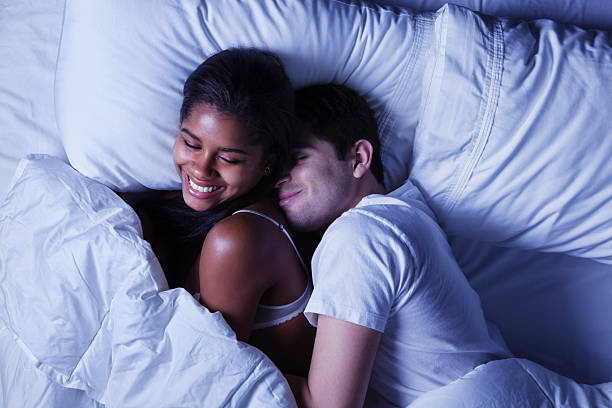 casal jovem feliz na cama - men sensuality photography high angle view - fotografias e filmes do acervo