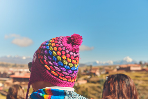 Back view of young traveler in hat standing over mountain peaks. Autumn traveling scene, wanderlust concept.