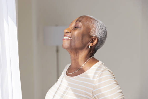 istock Senior Woman Smiling While Standing at a Window 1732521402