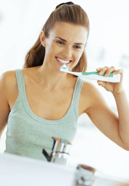 istock Happy young woman brushing teeth in bathroom 1732521587