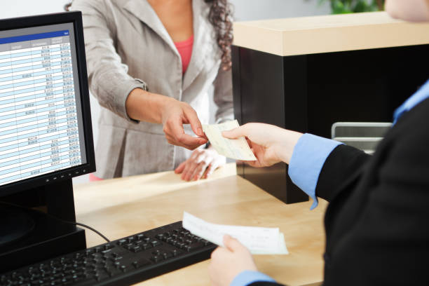 Bank Teller Service with Customer Deposit Transaction Over Business Counter stock photo