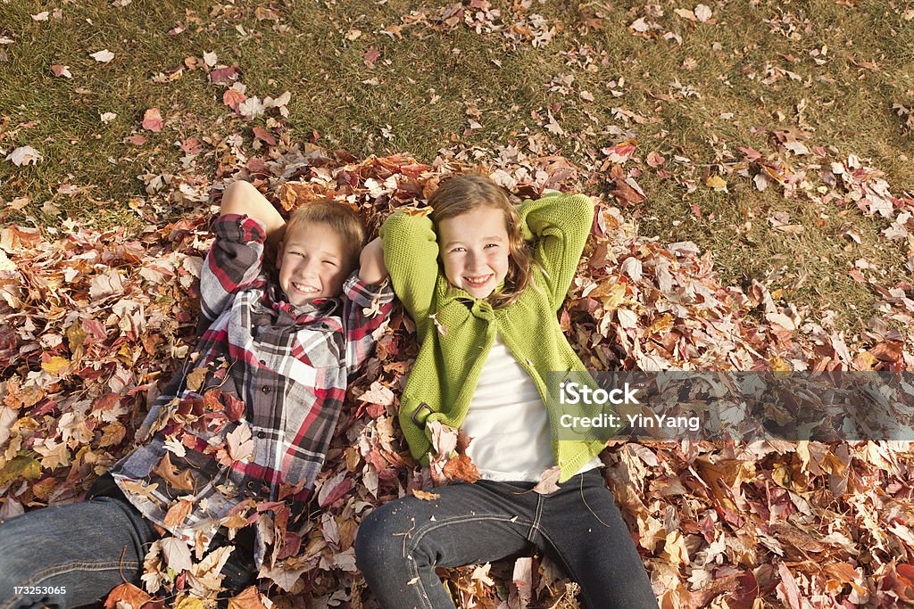 Enfants se détendre et se reposer sur un tas de feuilles d'automne Hz - Photo de Enfant libre de droits